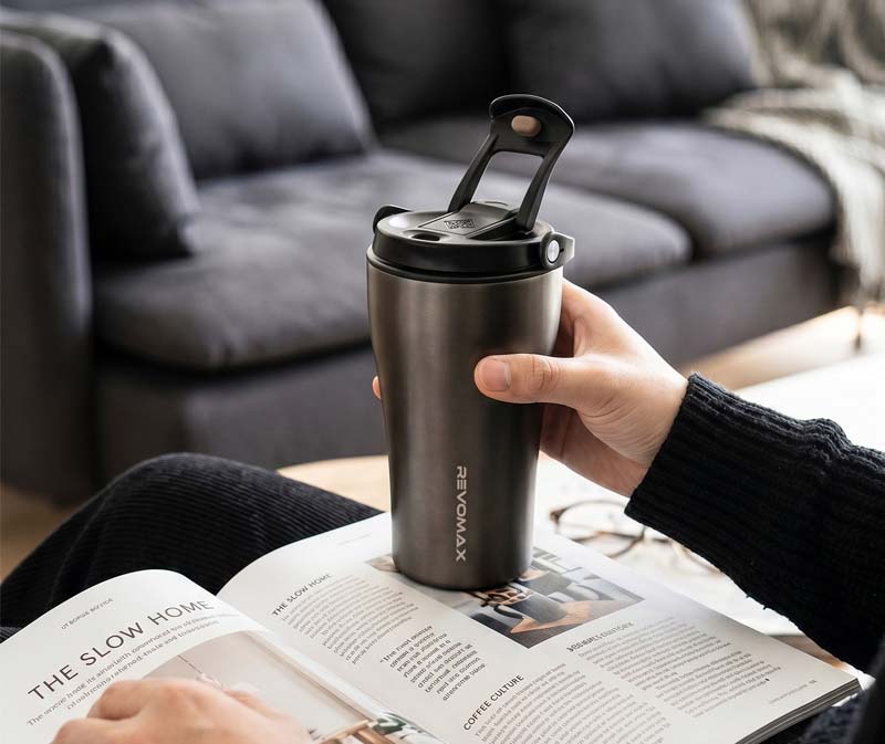 Relaxing at home holding an insulated no-screw coffee tumbler